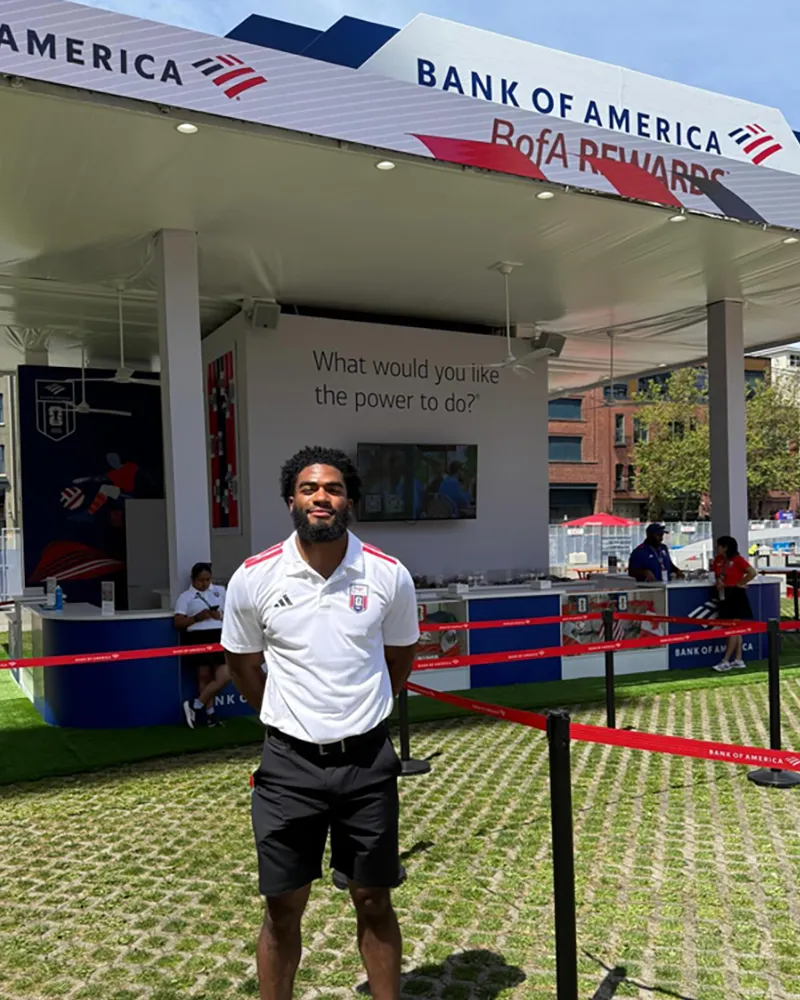 Jordan Mitchell standing in front of a Bank of America FIFA fan experience location.