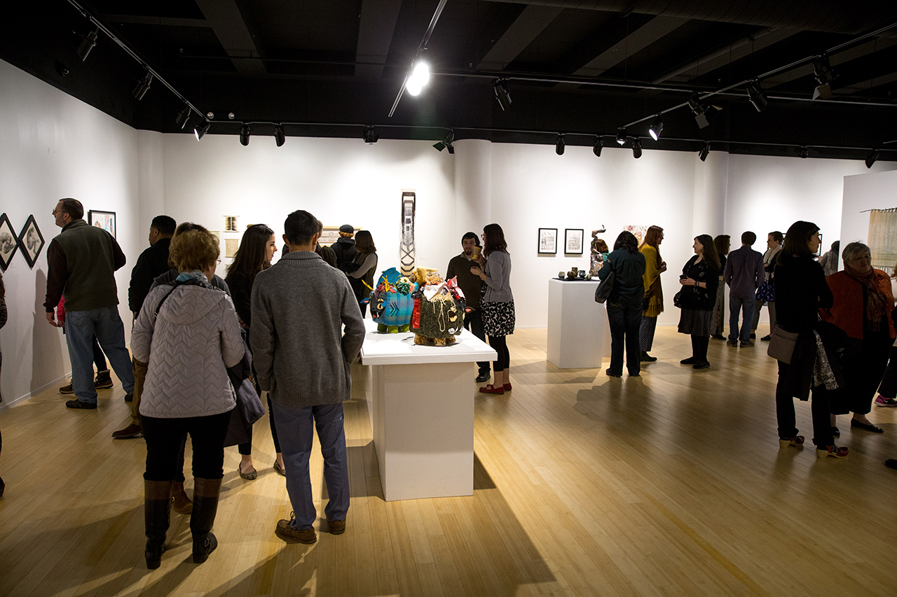 Gallery containing sculptures and paintings, full of spectators 