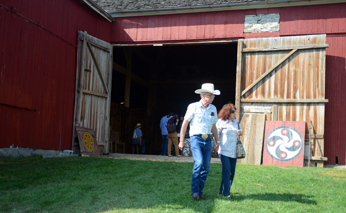 A man and a woman walking toge4ther in front of the entrance to a red barn