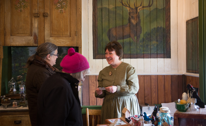 Female faculty smiling and chatting in a group in a front room with a painting of a deer