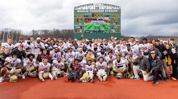 Golden Bear football players pose in front of the scoreboard at Slippery Rock