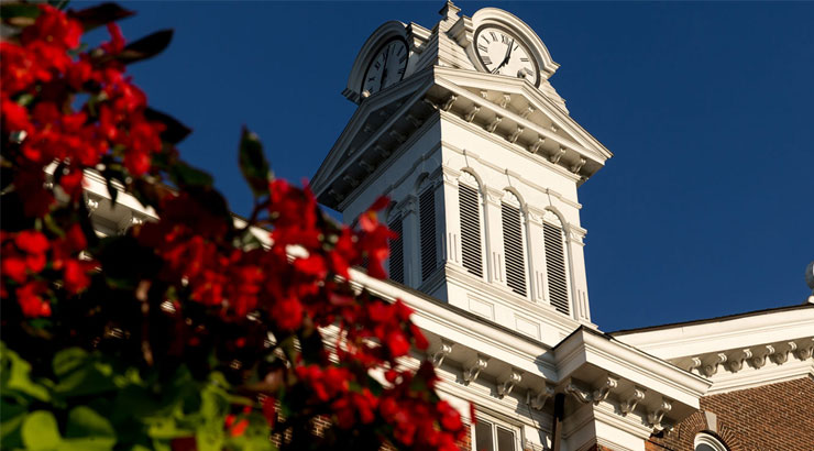 Old Main clock tower with a flowering tree in the foreground