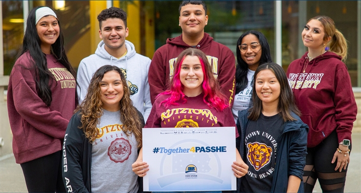 A group of KU students in 2 rows with 3 students in the front and 5 students behind them. One student in the front middle is holding a sign that says #Together4PASSHE. 