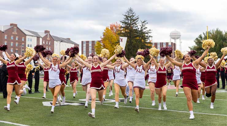 A picture of the Kutztown cheer team running onto the field.