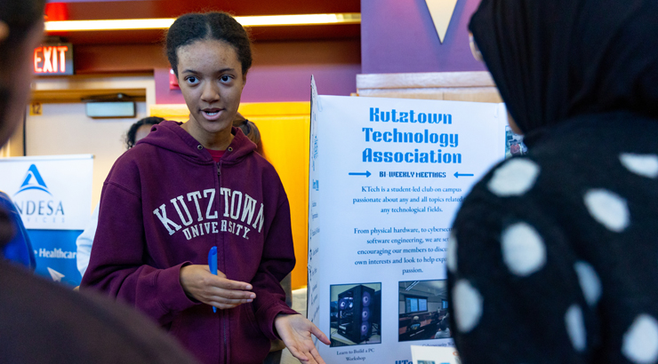 Female KU student talking with attendees at Kutztown University's Girls in STEM Symposium.