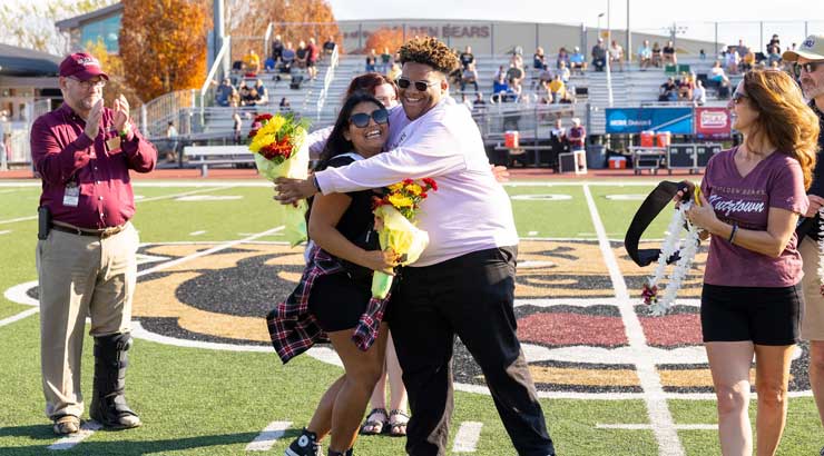 Homecoming spirit awardees Maria Del Carmen Angeles-Molinelli and Randy Garcia De Jesus celebrate with President Hawkinson and others at Homecoming game.