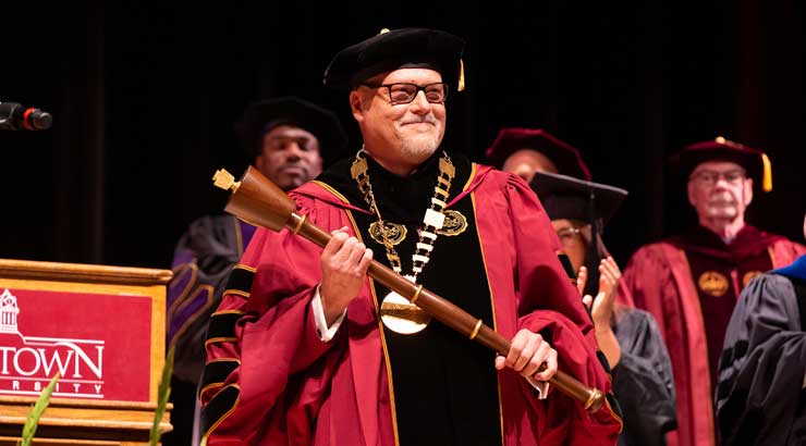 President Cavalier smiles holding the presidential mace at inauguration.