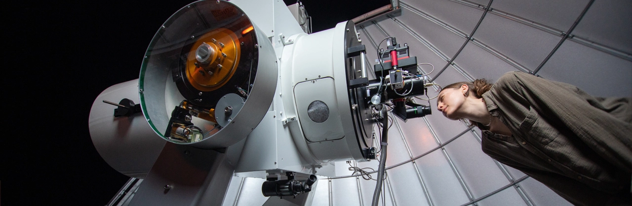 A female Kutztown University student looking into the main telescope of the observatory in the grim science building