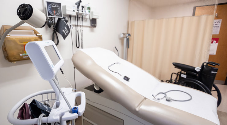 A medical exam room with a table, wheelchair, and various medical instruments used to examine a patient