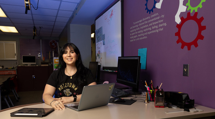 woman sitting at a desk with a laptop smiling and looking at the camera