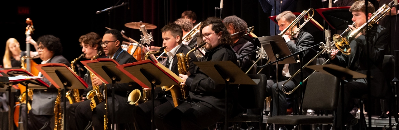 students performing on stage with various instruments