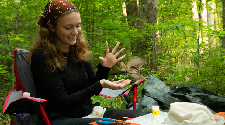 a female biology major releasing a bird she just measured and documented