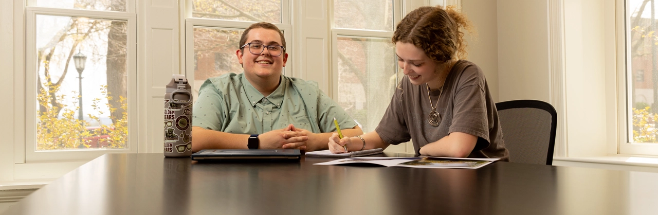 a male and a female sitting at a table working on a project