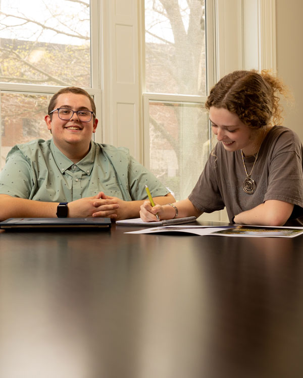 female student holding binder looking at brochure with older male