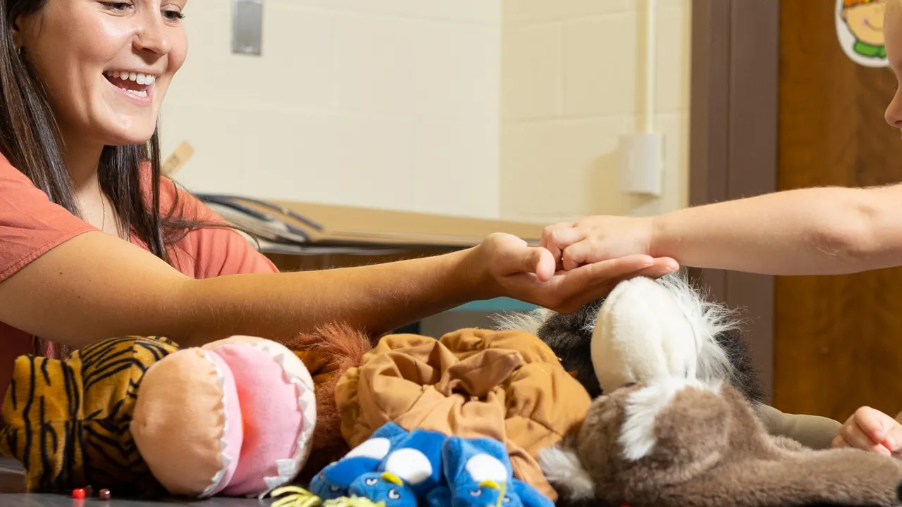 Female teacher works with child in an education setting.