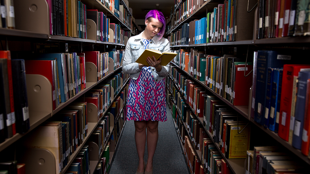 female student holding book in library