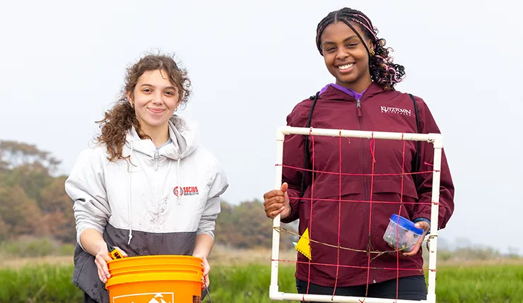 two female students holding tools to collect research.