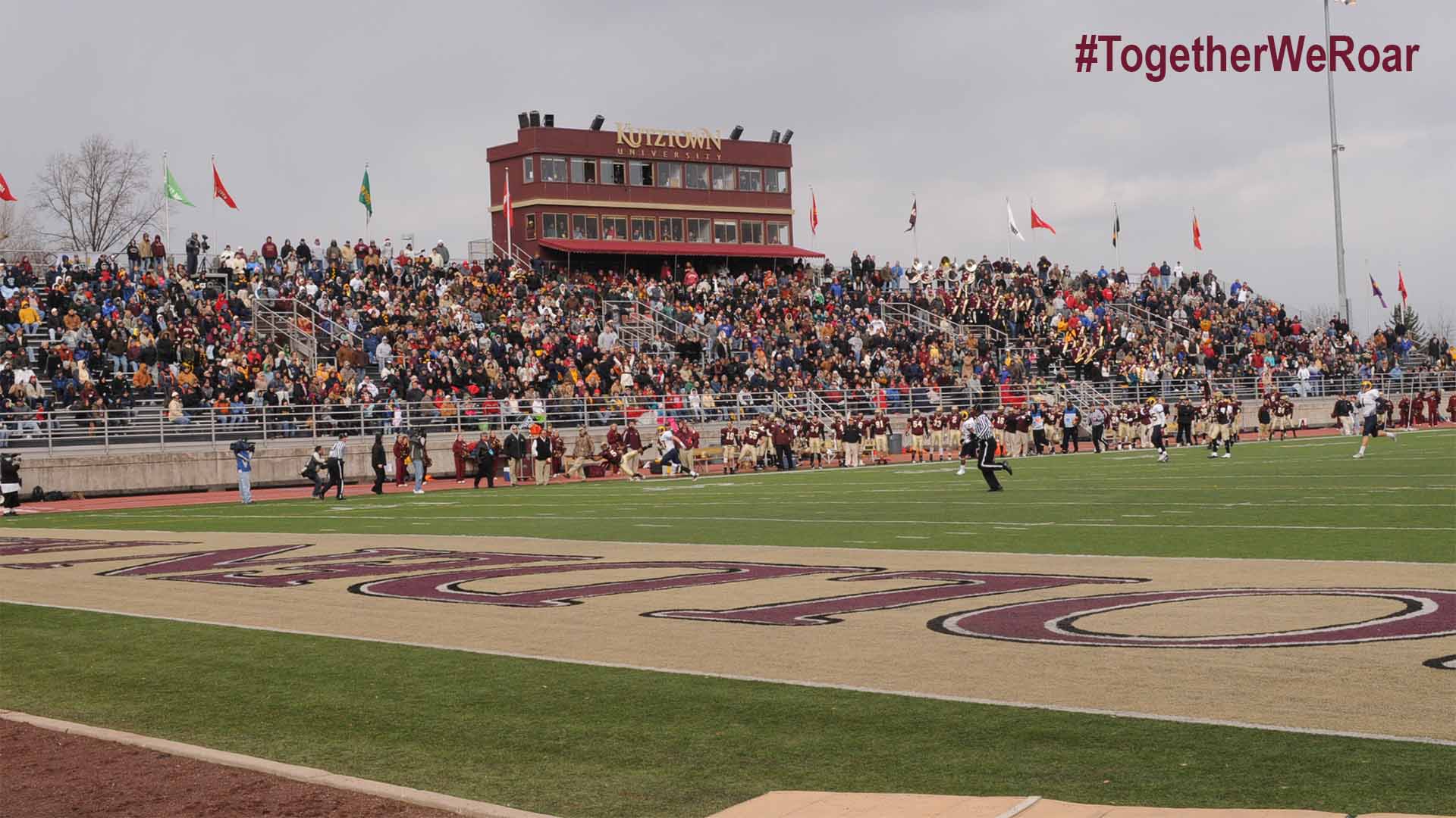 The end zone of the football field during a football game with the stands full of cheering fans in the background