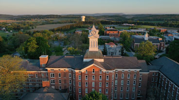 aerial view of old main, with the iconic clock tower in the middle, beyond is a view of north campus and the surrounding countryside.