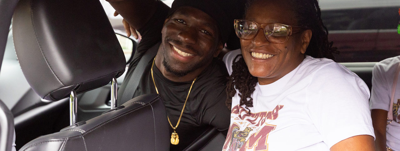 Kutztown University student and mom, wearing a Kutztown Mom T-shirt, smile at the camera.