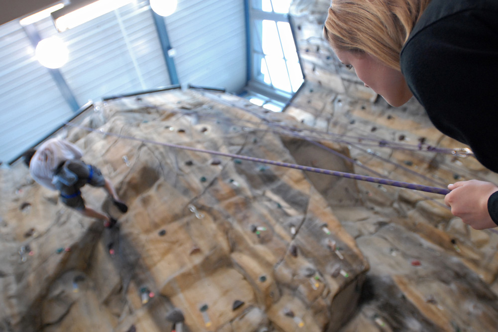 view from below as climber scales rock wall