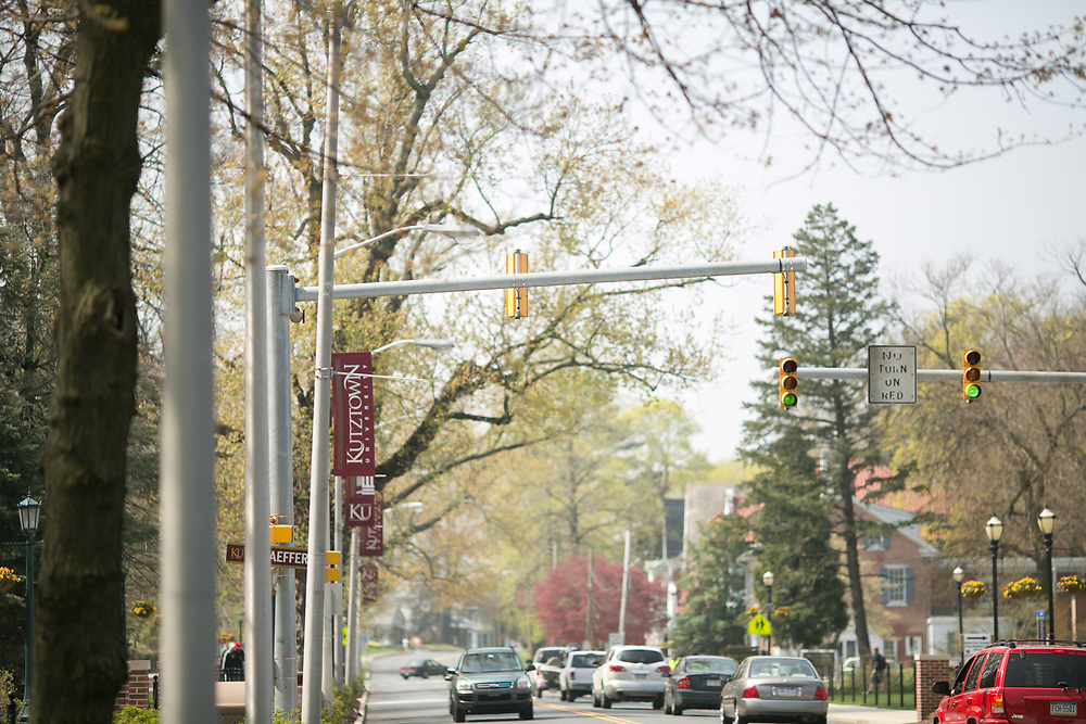 A view of Main Street on campus wiht cars driving along the way, street signs and traffic lights are visible.