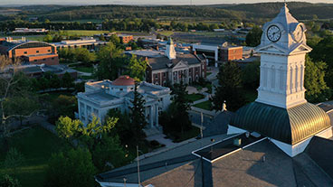 An image from above the old main tower with the tower in the forefront and the academic building in the background as well as the sprawling green countryside and mountains