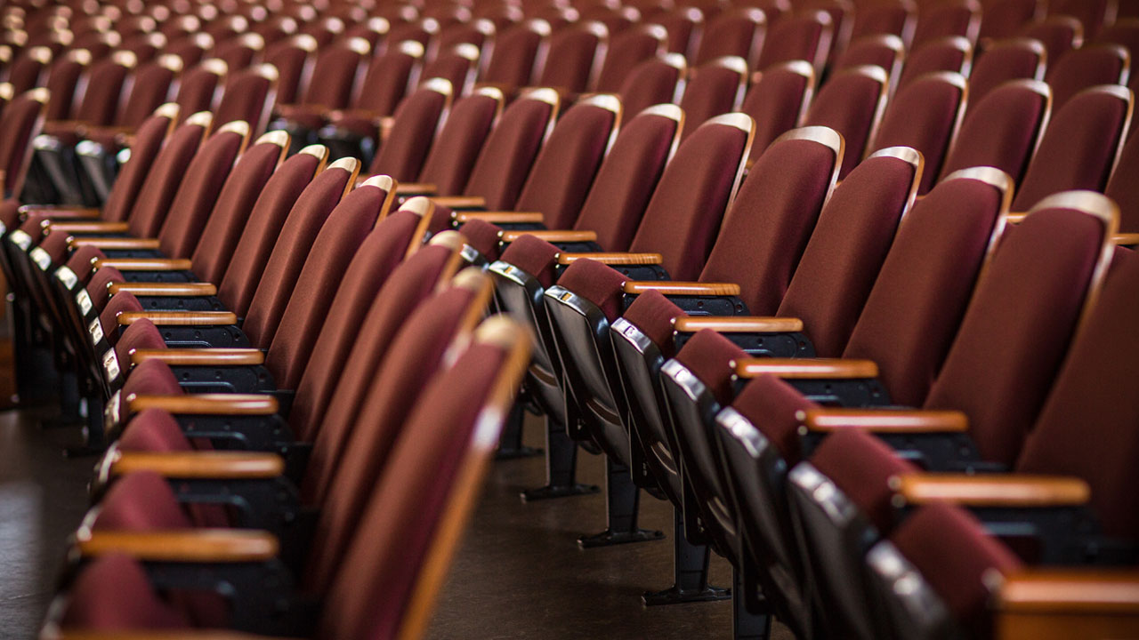Closeup on three rows of empty auditorium seats